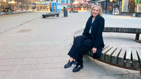 Henkilö istuu penkillä Tuomiokirkonkadulla Tampereella.