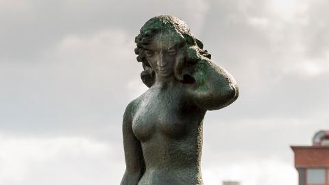 Wäinö Aaltosen Suomen neito-patsas vyötäröstä ylöspäin harmaata taivasta vasten.