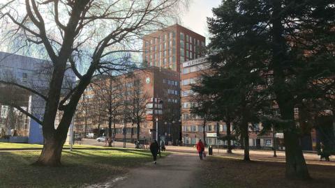 Kuvassa puistonäkymää ja punatiilisiä rakennuksia.