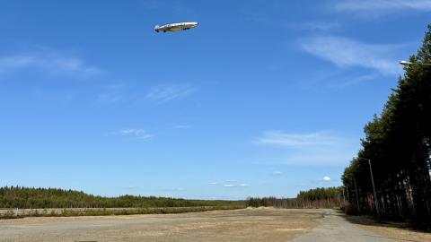 Ilmalaiva lentää peltoaukion yllä. 