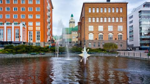 Lammessa oleva tähden muotoinen taideteos, vieressä suihkulähde.