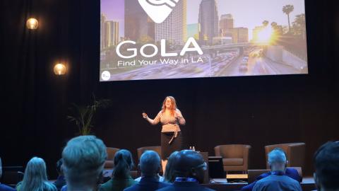 Nainen pitää puhetta tapahtumalavalla.