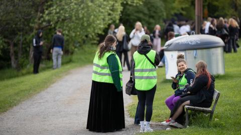 Vihreäliiviset jalkautuvat nuoriso-ohjaajat juttelevat nuoren kanssa puistossa penkin ympärillä