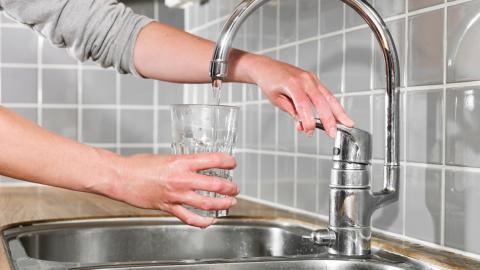 Ihminen laskee hanasta vettä lasiinsa.