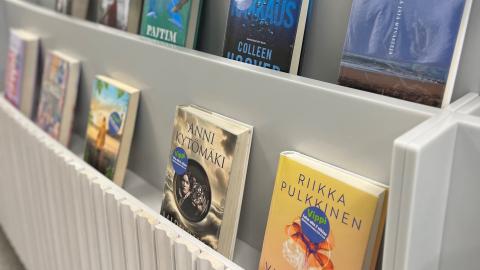Kirjoja nojaa valkoista hyllyä vasten kannet katsojaan päin. Kansissa tarra &quot;Vippi&quot;.