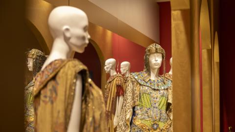 Rooman oopperan pukuja näytteillä museossa. Kullansävyiset puvut on puettu valkoisten mallinukkejen päälle.