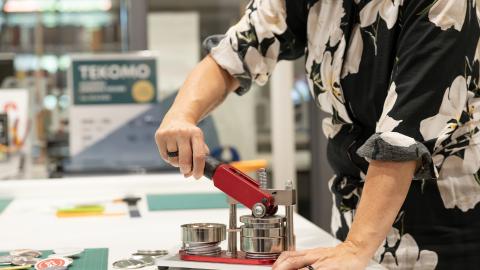 Henkilö käyttää yhteiskäyttöistä pinssikonetta.