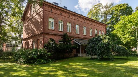 Hatanpään kartanon konttorirakennuksen punatiilinen julkisivu ja piha-aluetta.