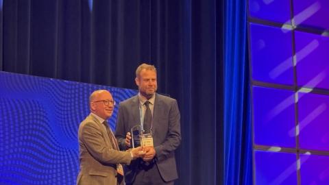 Mies ojentaa palkintoa toiselle miehelle palkintogaalan lavalla.