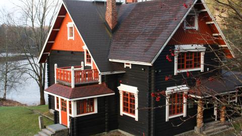 Hirsitalo, jossa on kaksi kuistia. Taustalla on järvi.