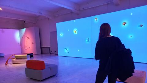 Ihmishahmo seisoo sinisävyisessä galleriatilassa katsomassa taideteosta.