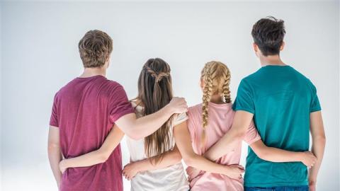 Neljä nuorta on selin katsojaa kohti. He pitelevät toisistaan kiinni kädet selkäpuolella.