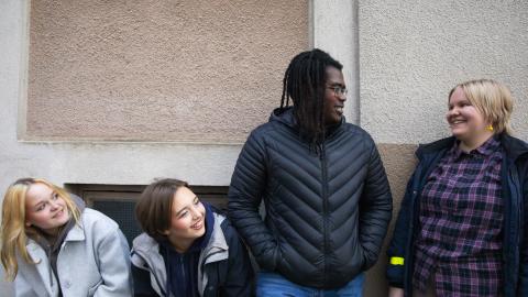 Joukko nuoria iloisena vaalean seinän edessä