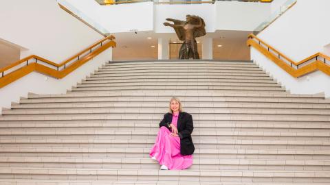 Henkilö istuu portailla. Taustalla ylätasanteella on patsas.