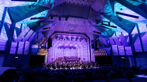 Tampere Filharmonia konsertoimassa Tampere-talon Isossa salissa. Salissa sinisävyinen valaistus.