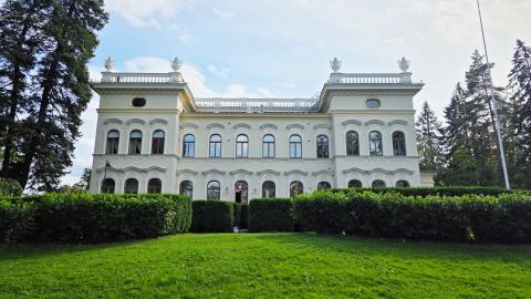 Museo Milavida kuvattuna Näsijärven puolelta. Vaalea kolme kerroksinen kivirakennus, edustalla vihreitä pensaita ja nurmikkoa. 