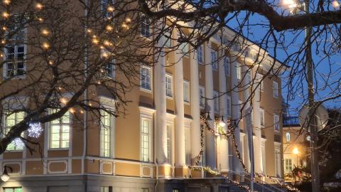 Keltainen iso rakennus hämärässä valaistuksessa talvella.