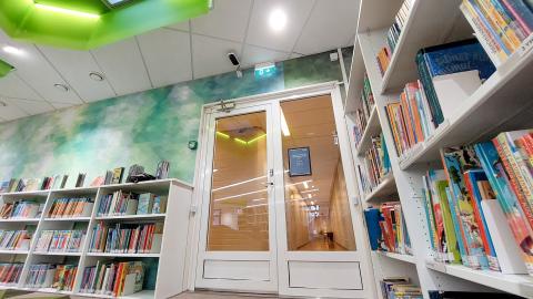 Musta-valkoinen kävijälaskuri kirjaston lasiovien oviaukon yläpuolella.