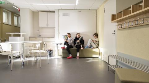 Kolme lasta istumassa ja lukemassa Kissanmaan koululla