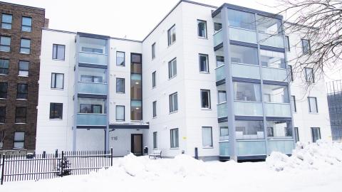 Valkoinen kerrostalo, jossa on lasitetut parvekkeet.