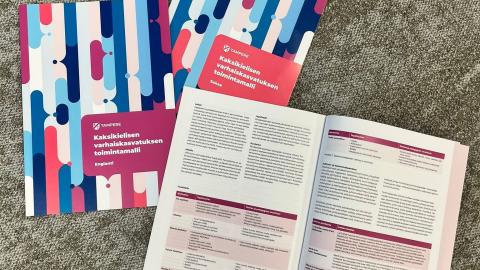 Three books on a carpet, one of which is open at the middle flap.