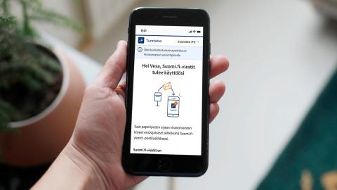 Ihmisellä kädessään puhelin, jonka avulla hän on tunnistautumassa suomi.fi-palveluun..