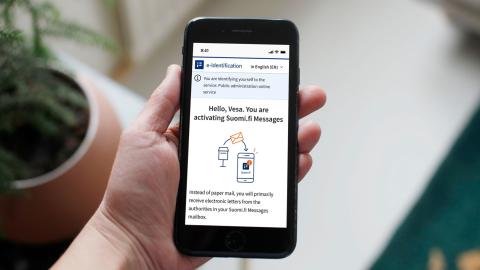A person is holding a phone, and the screen displays instructions on how to set up Suomi.fi messages.