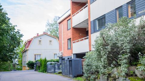 Pienkerrostalo ja omiakotitalo vierekkäin kesäisessä kadunvarsimaisemassa.