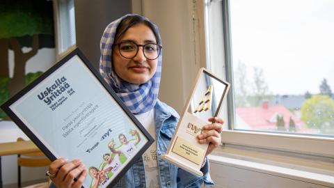 Hasanat Sultani esittelee kahta palkintoaan Hatanpään koulun luokkatilassa.