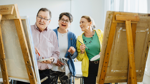 Three people are standing next to their easels.