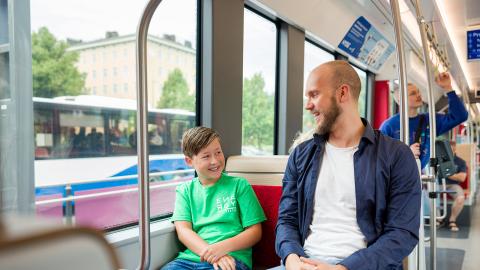 Mies ja poika istuvat bussissa, jonka ikkunasta näkyy toinen bussi.