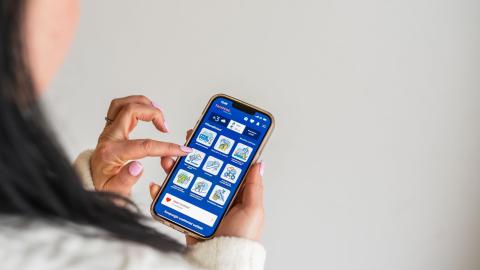 A woman with pink artificial nails is using the Tampere.Finland app on her phone.