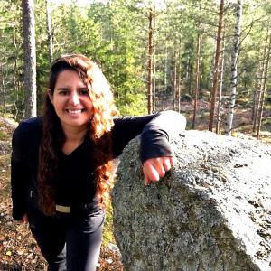 Catherine Ghersi nojaa isoon kiveen metsän keskellä 