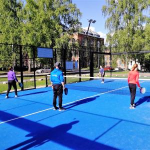 Nuoret pelaavat padelia liikunnanohjaajan kanssa.