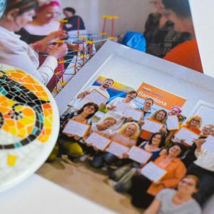 Two photographs of people on the table. There is also a colorful ceramic piece on the table.