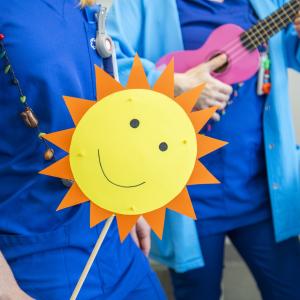 Siniseen paitaan pukeutunut henkilö pitelee auringon muotoista viiriä.