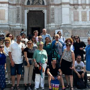 A group of people is standing on the steps of an old building.