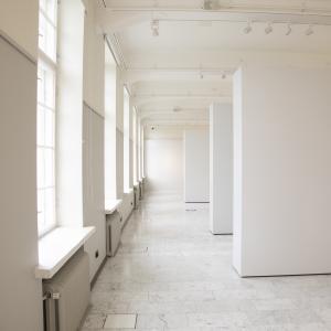 Isossa galleriatilassa on toisella seinällä ikkunoita ja kolme valkoista seinäkettä.