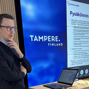 Henkilö seisoo ja kertoo tutkimuksesta seminaarissa.