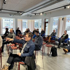 Henkilöitä istumassa kokoustilassa.