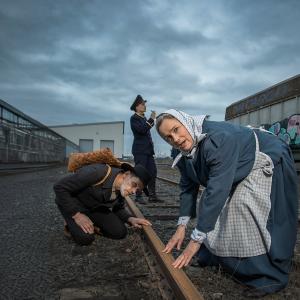 Rautatie-näytelmän hahmot ihmettelevät junaraiteita.