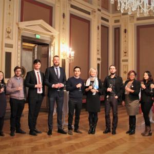 A group of people standing in a row in a stylish environment with wine glasses in their hands.
