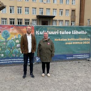 Jaani Haapasalo ja Annamaija Saarela seisovat ulkovaatteissa Nekalan kulttuurikeskuksen työmaan edessä. Taustalla lakana, jossa lukee &quot;Kulttuuri tulee lähelle&quot;.