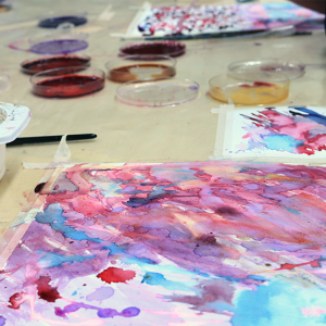 Kuvataidetyö ja luonnonväripurkkeja pöydällä.