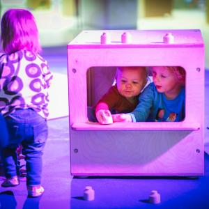 Kolme taaperoa leikkimässä näyttelyssä. 