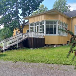 Keltainen kartanorakennus, jonka takana lasierkkeri.