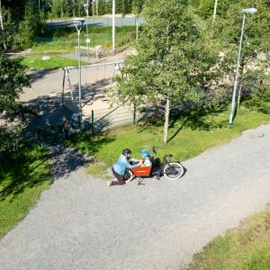 Parent and children outside the playground on cargo bike.