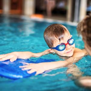 Pieni poika harjoittelee uimista uimalaudan avulla.