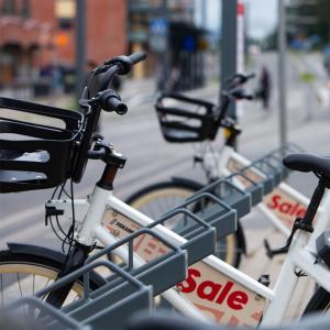 Kaksi kaupunkipyörää kaupunkipyöräasemalla. 