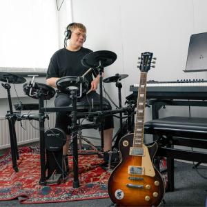 Henkilö soittaa sähkörumpuja, edustalla muitakin soittimia.